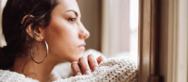 Woman looking out the window trying to deal with trauma