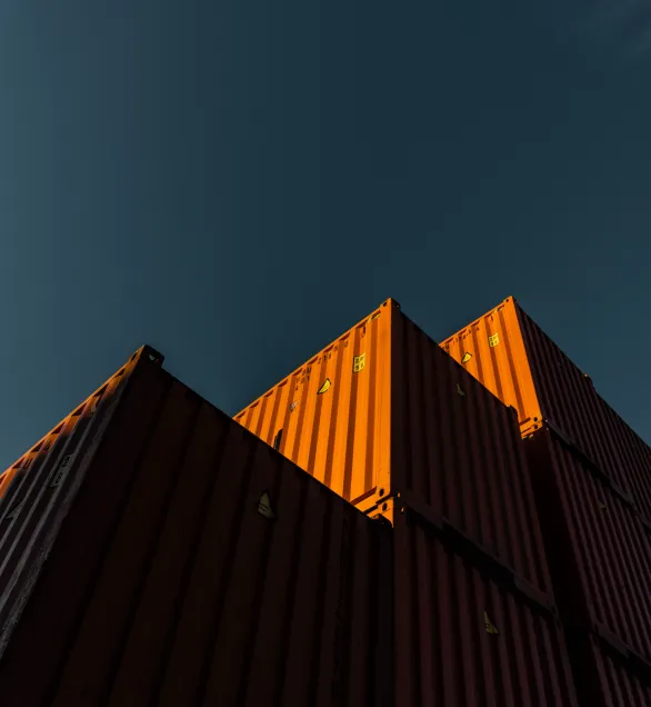 Tre frakt containere som står på hverandre, lyset treffer forsiden