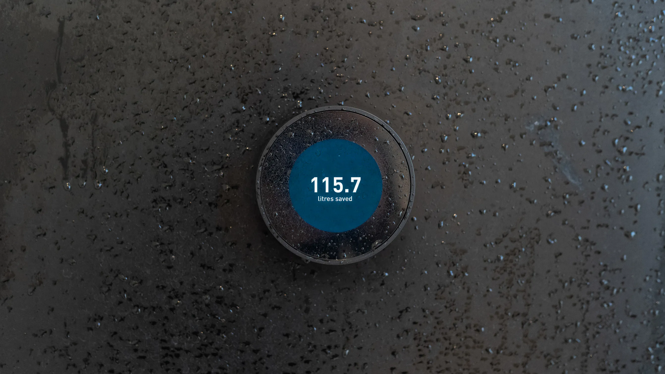 Black and blu round control with text 115.7 litres saved on black wet walll