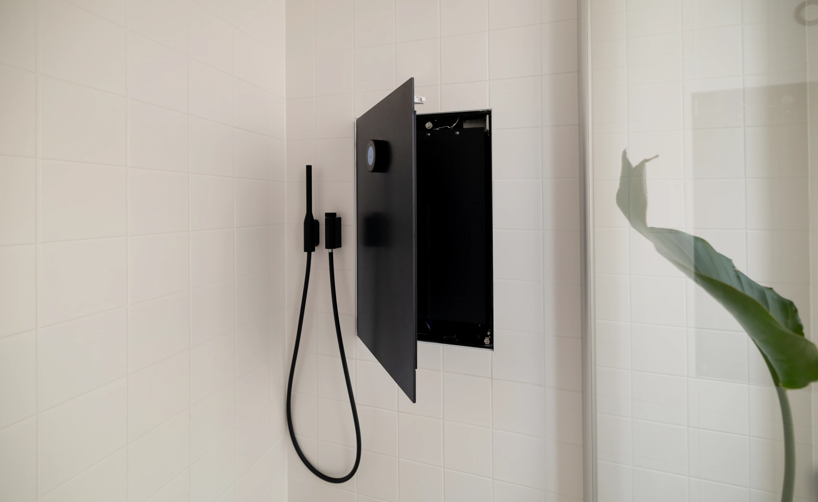 Handdusch med slang och svart öppen lucka på vit vägg