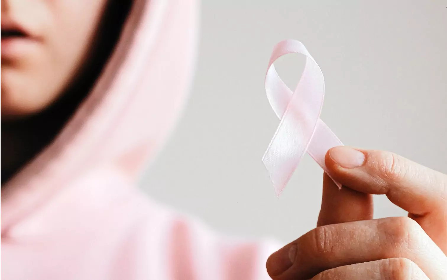 a person holding a pink ribbon