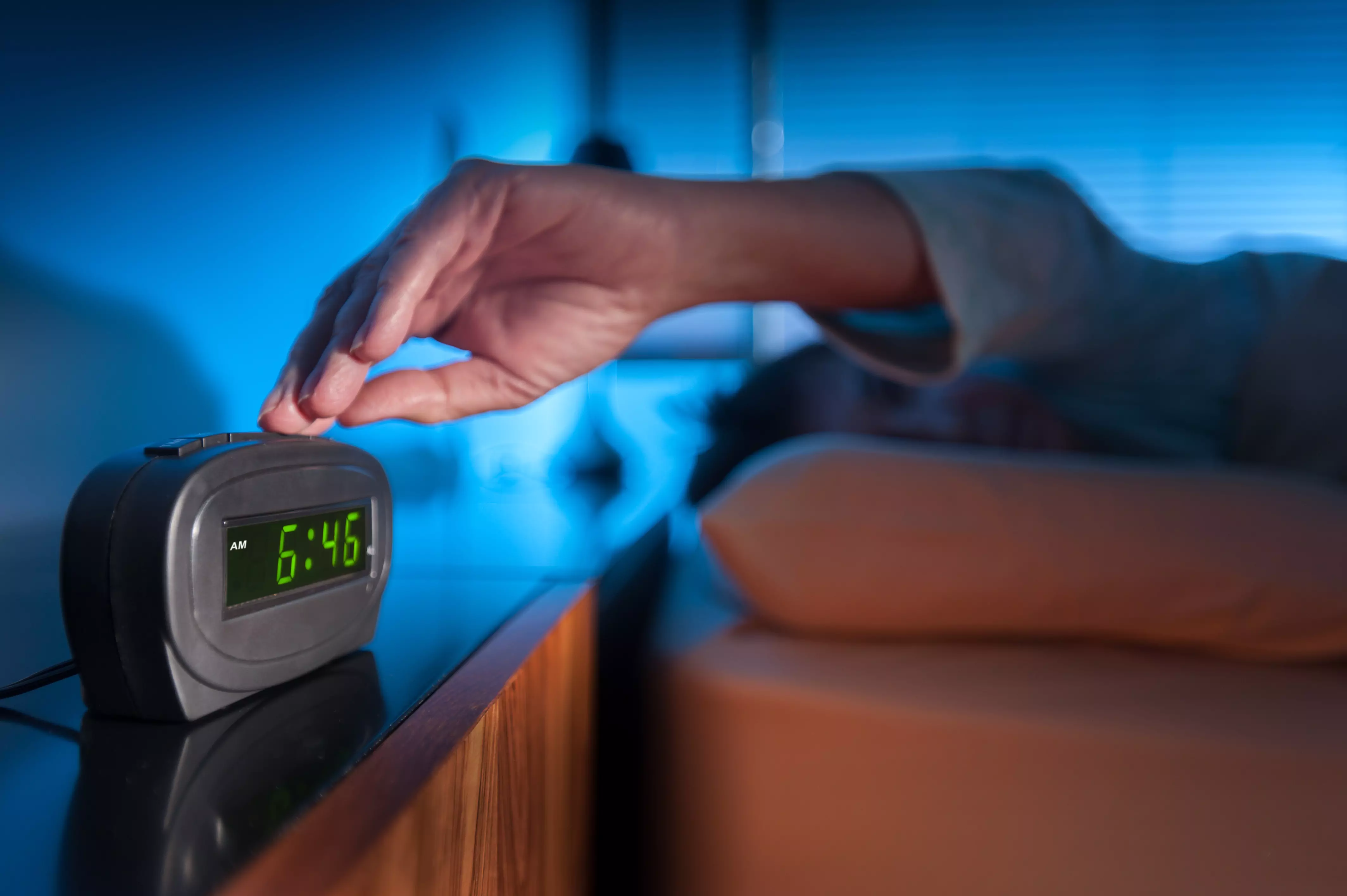 a person laying in bed and turning off an alarm