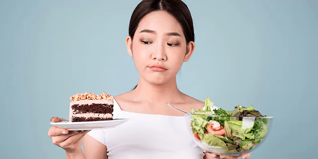 a person holding a plate with a cake with one hand and a bowl of salad with another