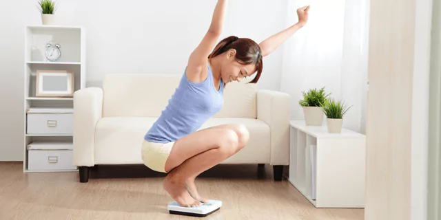 a person weighing themselves on a scale and looking happy