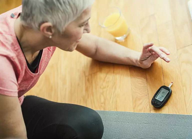 Woman checking her blood glucose with finger prick method