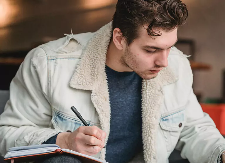 Person writing in their blood sugar log notebook
