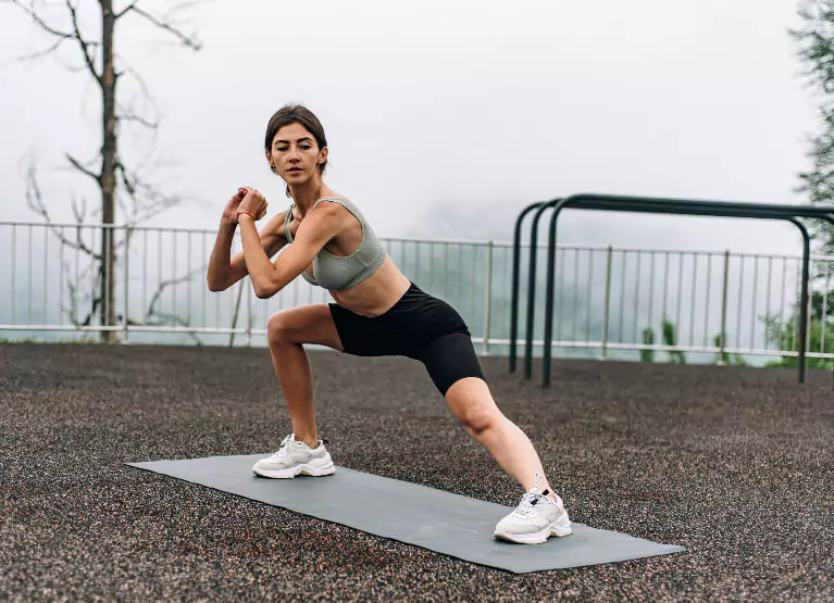 Woman doing side lunge stretches in playground