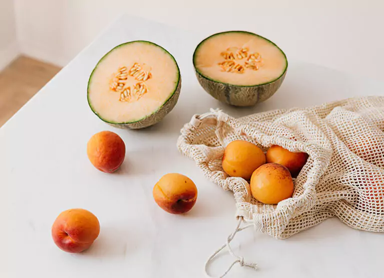 Oranges and a cantaloupe cut in half on white kitchen table