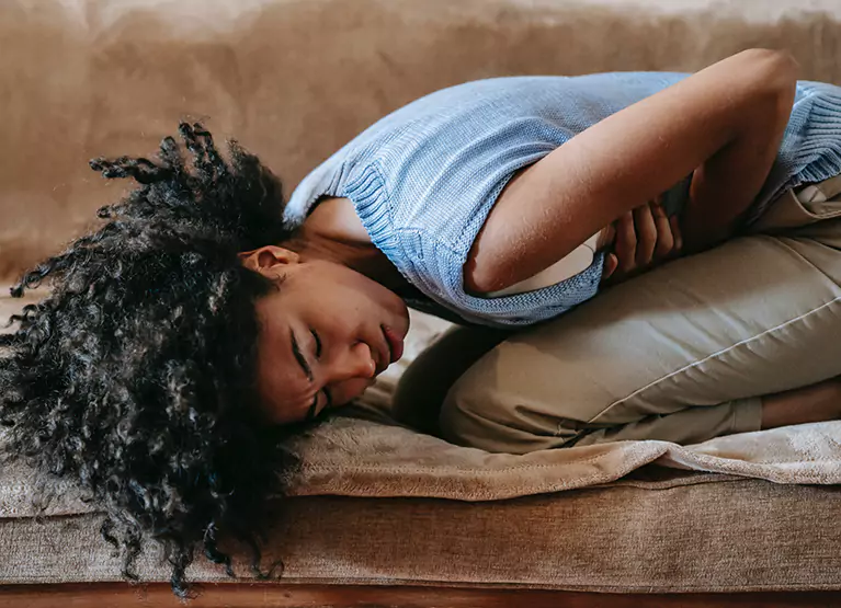 a girl laying down and holding her stomach in pain