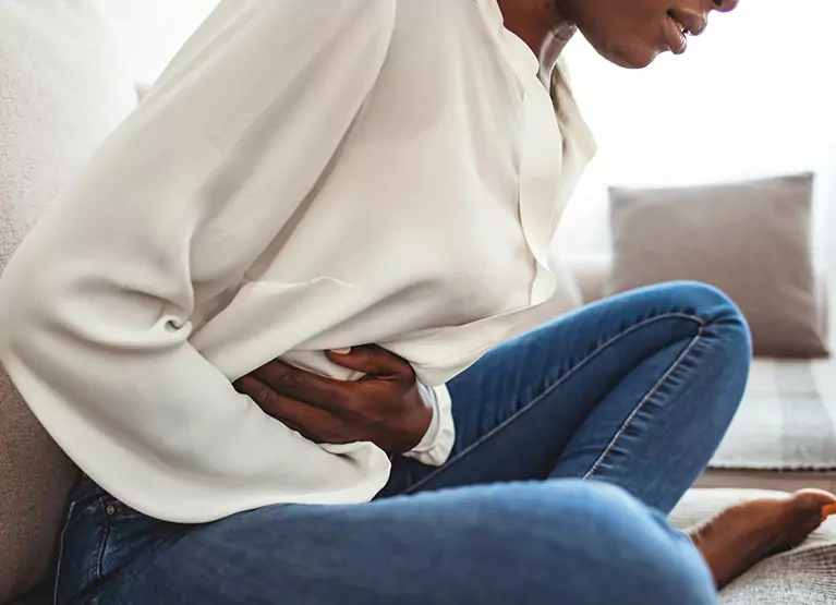 someone sitting on the couch and holding their stomach