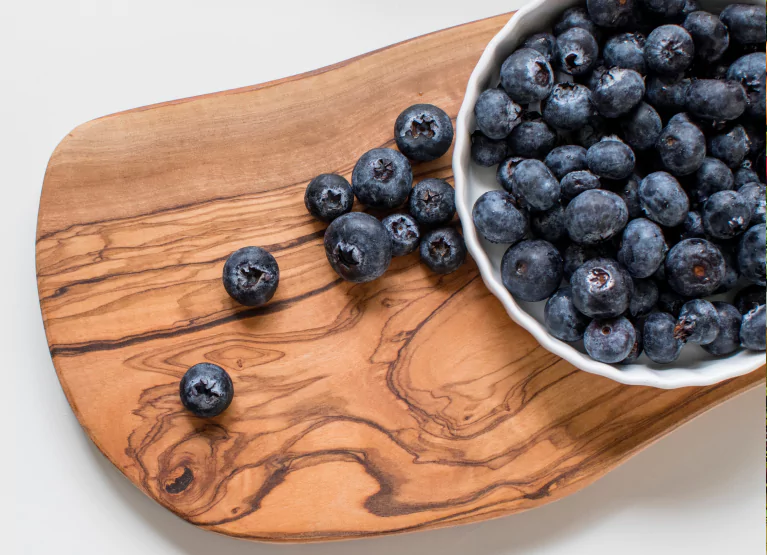 a cutting board and bowl of blueberries