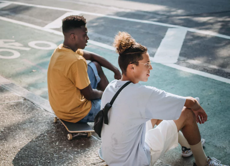 Two people sitting on sidewalk