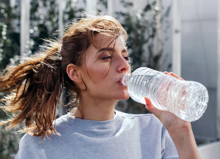 Redhead woman drinking water from bottle
