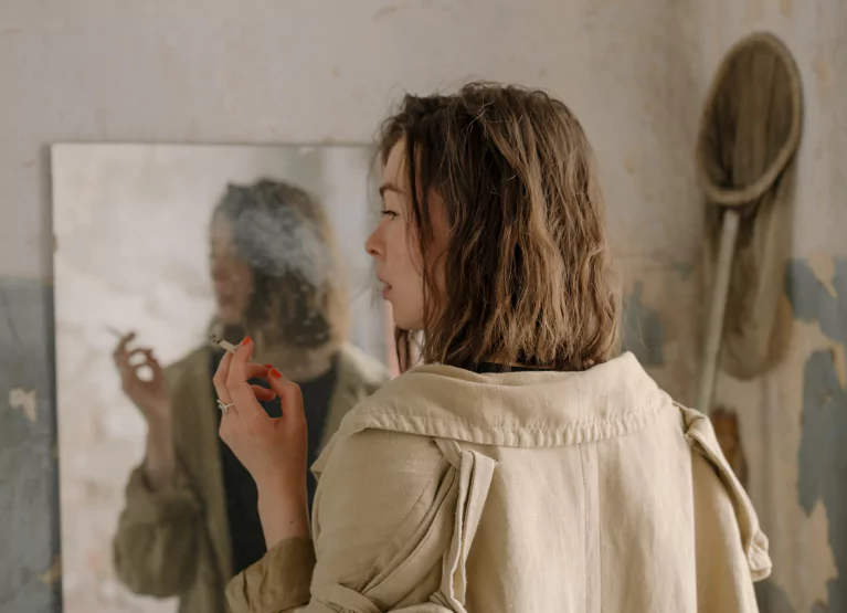 Woman smoking in front of mirror(s)