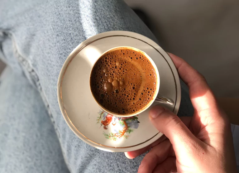 Teacup filled with espresso on person's lap