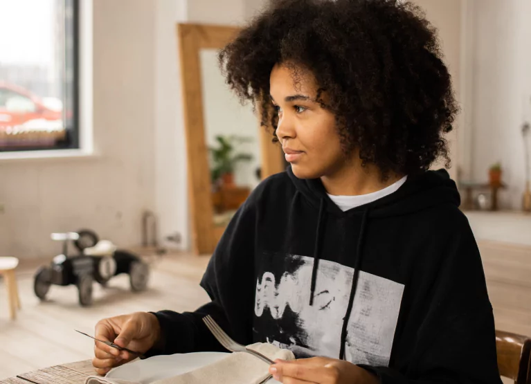 Woman sitting down at dining table with knife and fork in hand