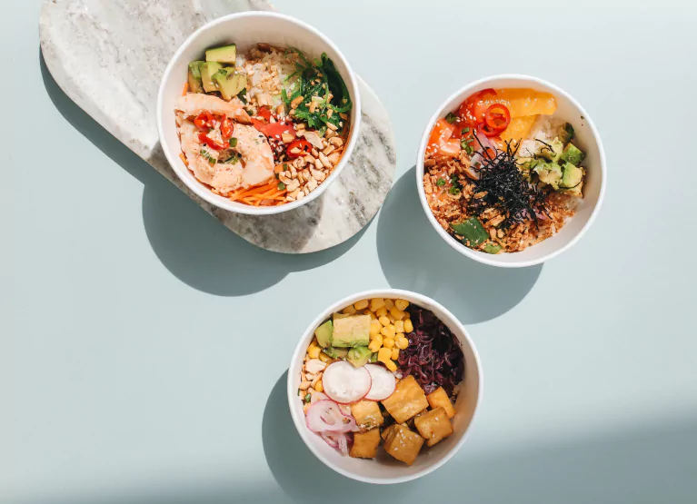 Bowls with rice, nuts, veggies, avocado, and protein