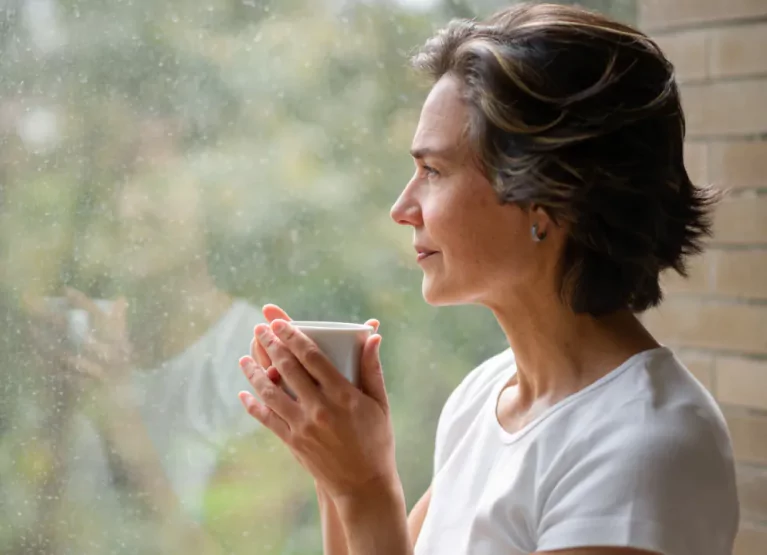 Woman with mug in hand looking out the window