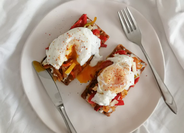 Plate of toast with poached eggs and vegetables