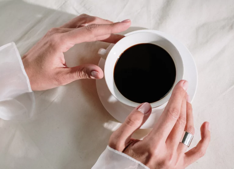 Person holding cup of black coffee