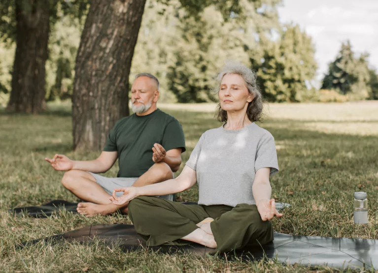 two people sitting and meditating in the park