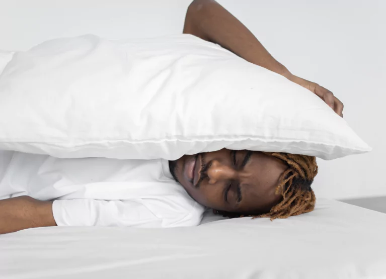 a boy with a pillow over his head and looking tired