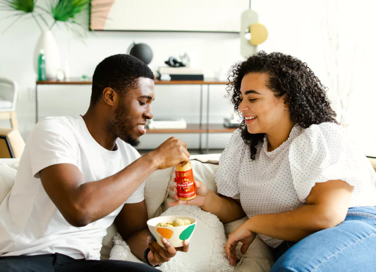 two people enjoying a snack on the couch