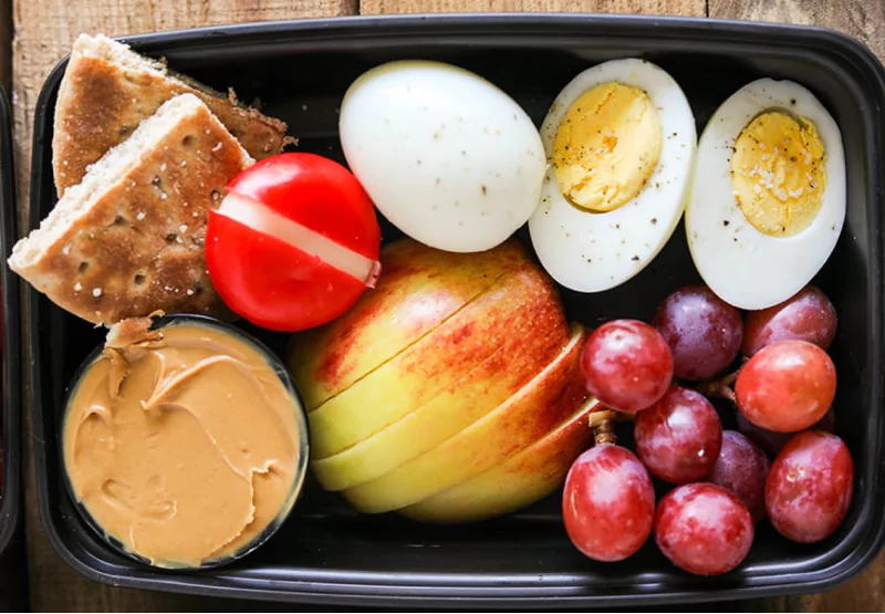 a lunch tupper with protein snacks and fruit