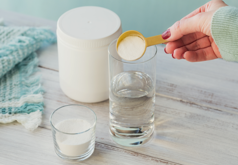 Person putting collagen powder into glass of water