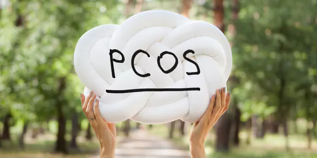 someone holding a knot with "PCOS" written on it