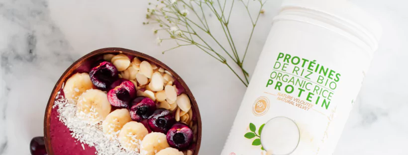 A box of rice protein near a bowl of fruit and nuts
