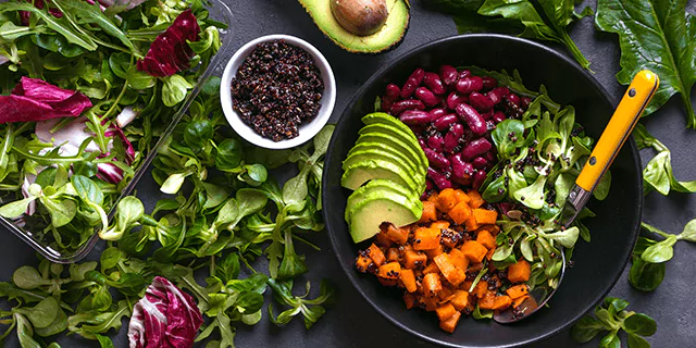 a plate of beans, cut avocado, green leafy vegetables and a bowl of chia seeds