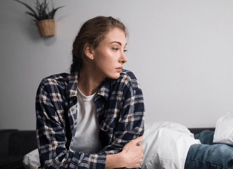 Someone in a plaid shirt with long blonde hair tied in a ponytail, looking stressed