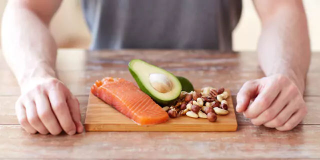 salmon an avocado and nuts on a wooden board