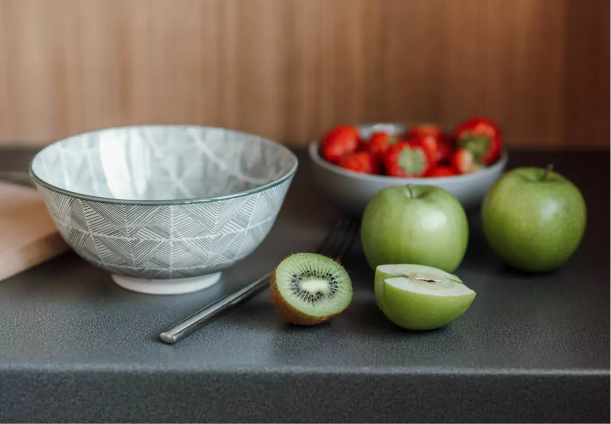 a bowl and apples, strawberries, and kiwi