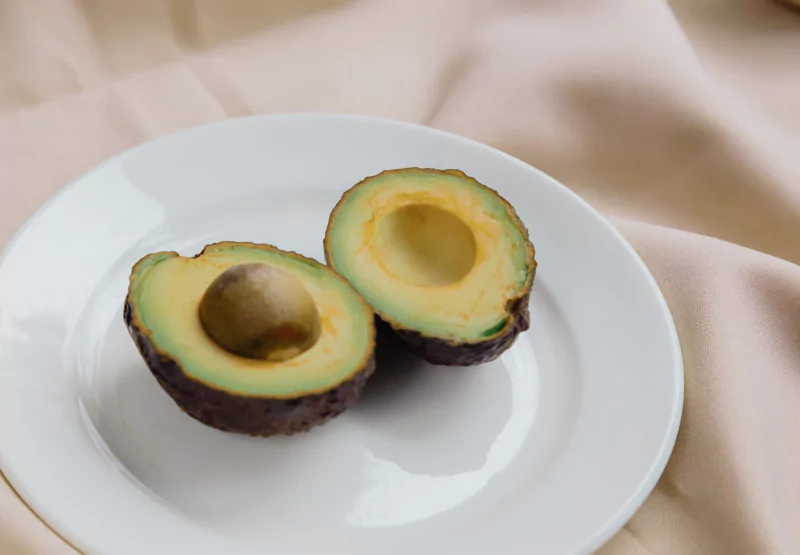 Two halves of an avocado on a white plate