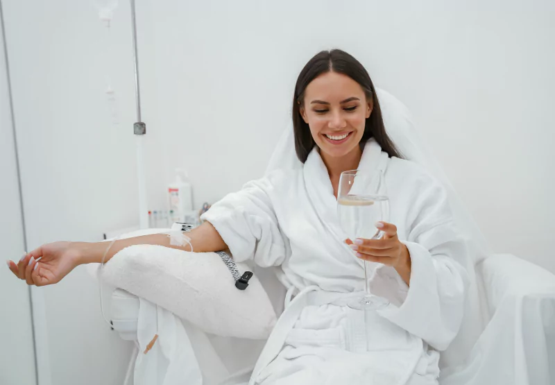 a woman getting an IV and drinking a glass of water