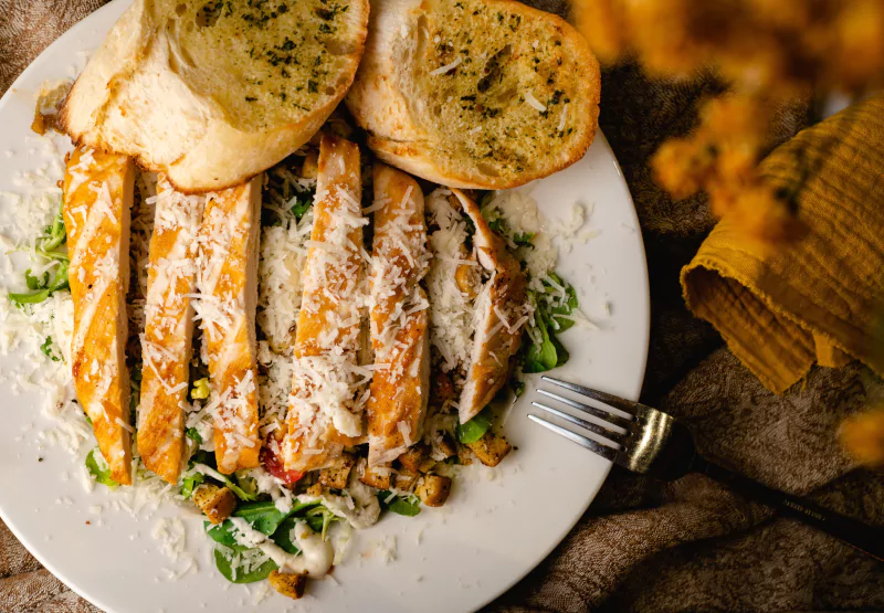 a salad bowl with bread and chicken on top