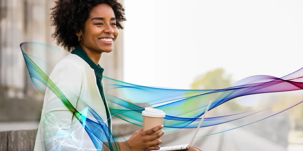 Businesswoman holding coffee and working on a laptop outside
