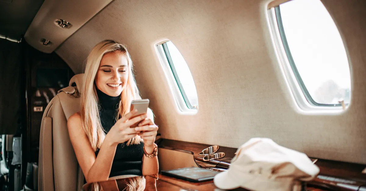 Celebrity women on private jet looking at smartphone in her hand.