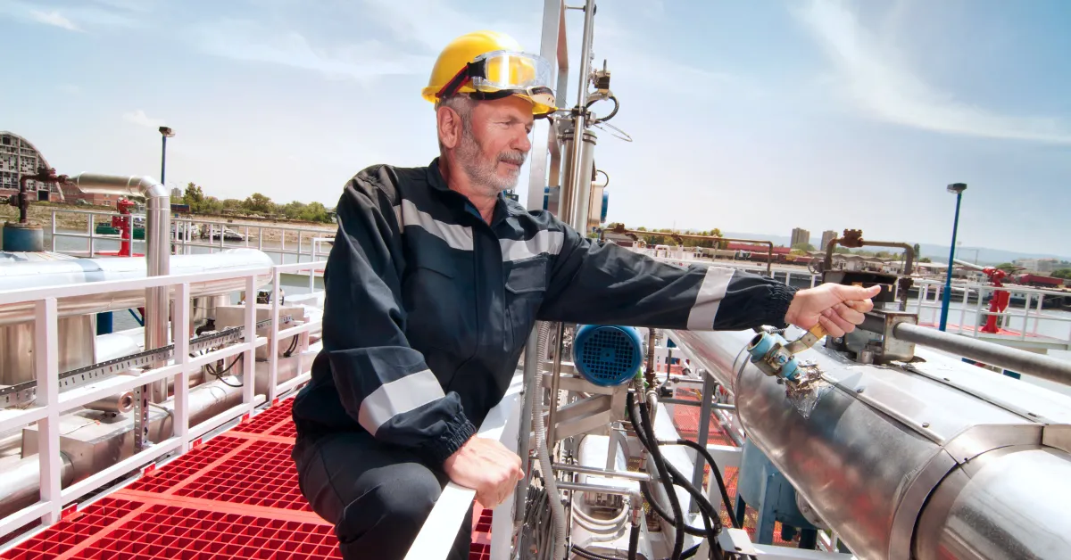 Oil company worker performing maintenance on pipes.