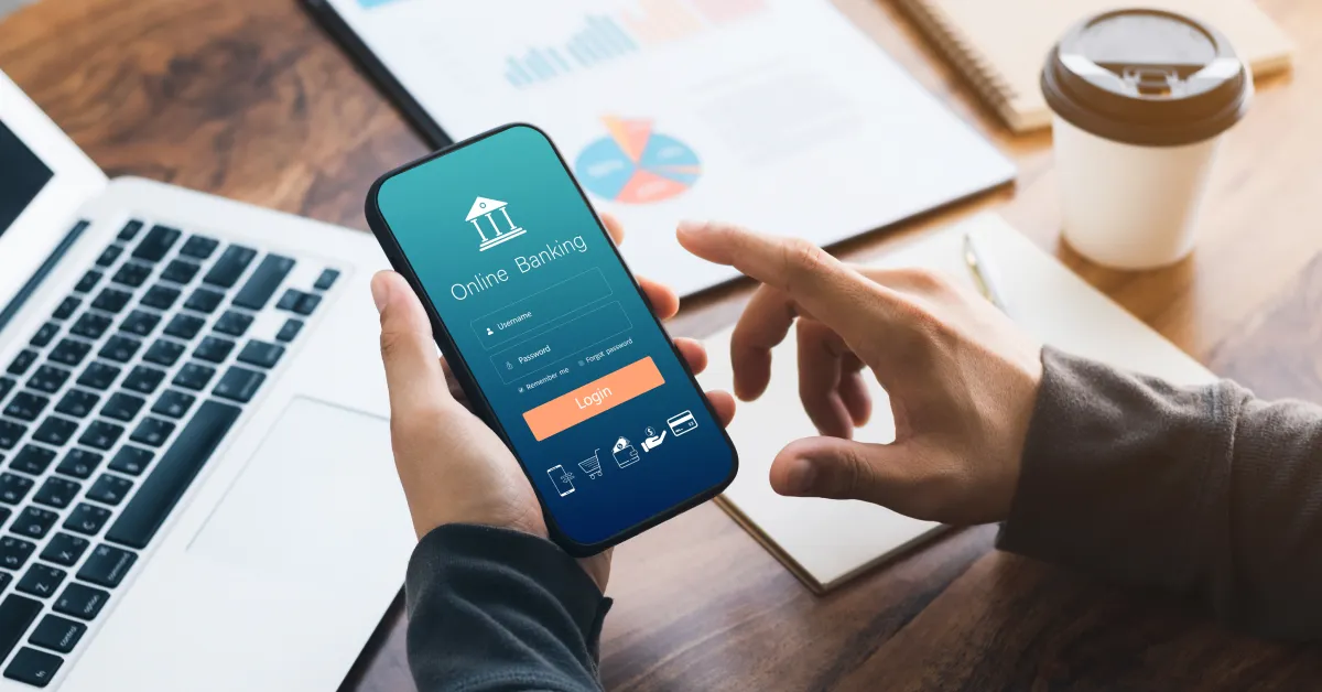 Person holding a phone with banking app open on screen.