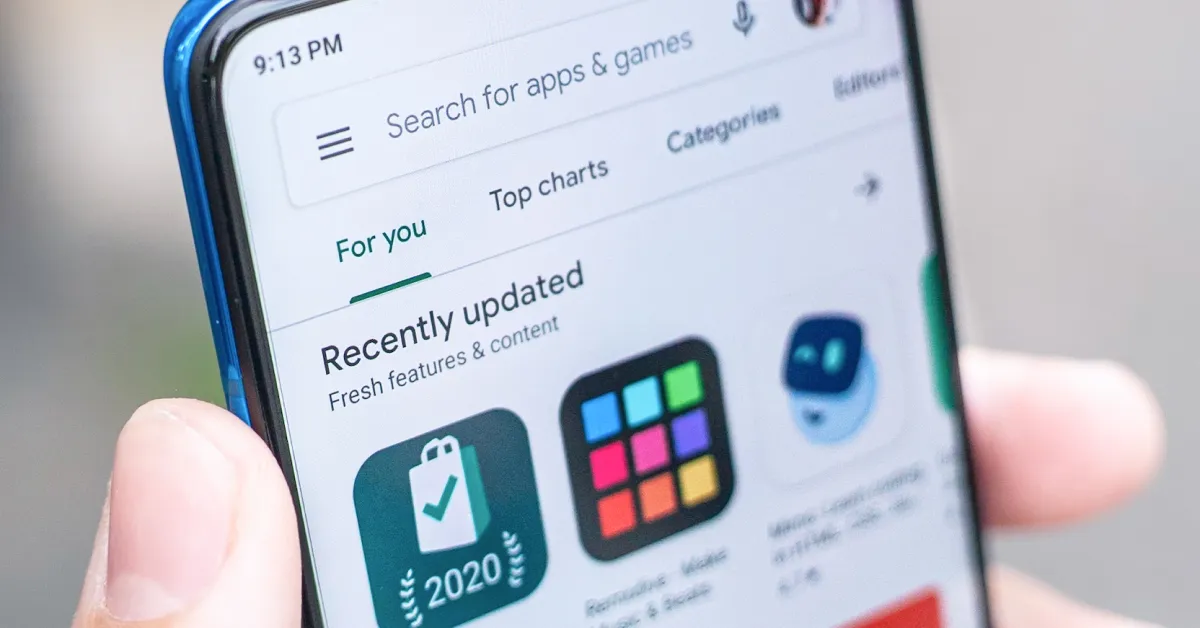 Person holding phone with google play store open on display.