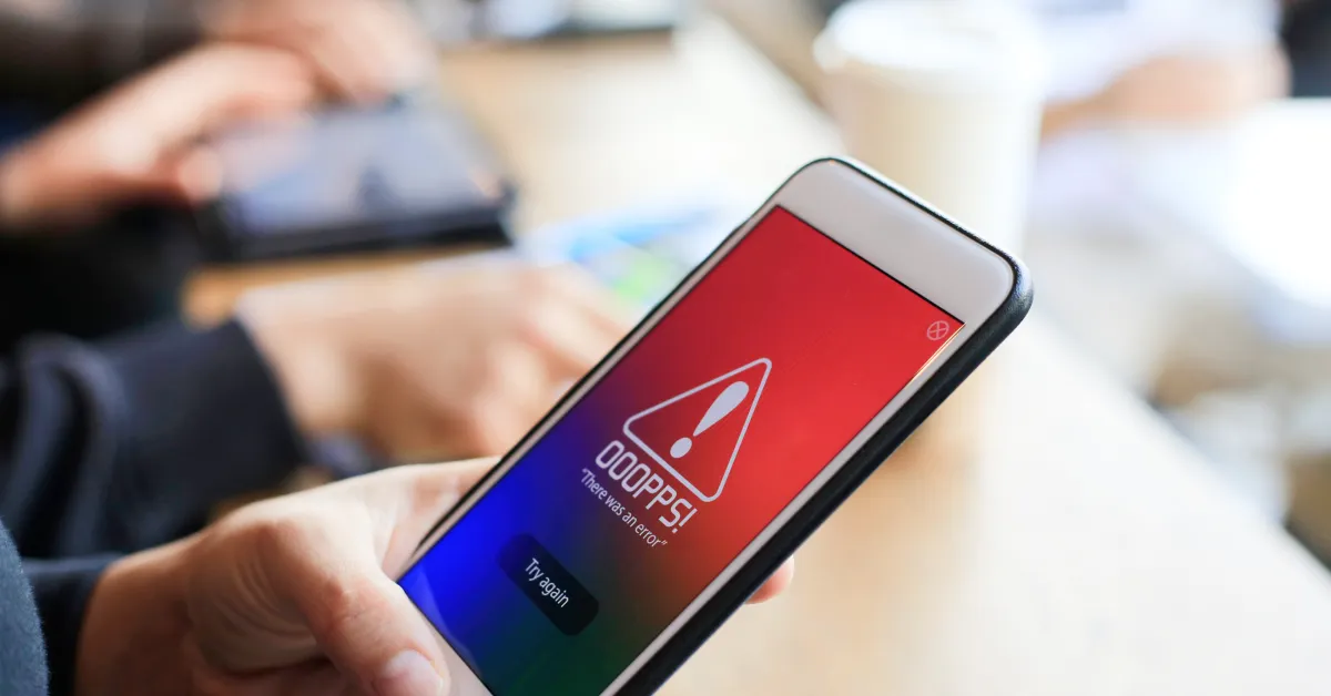 Person holding phone with error message displaying on screen.