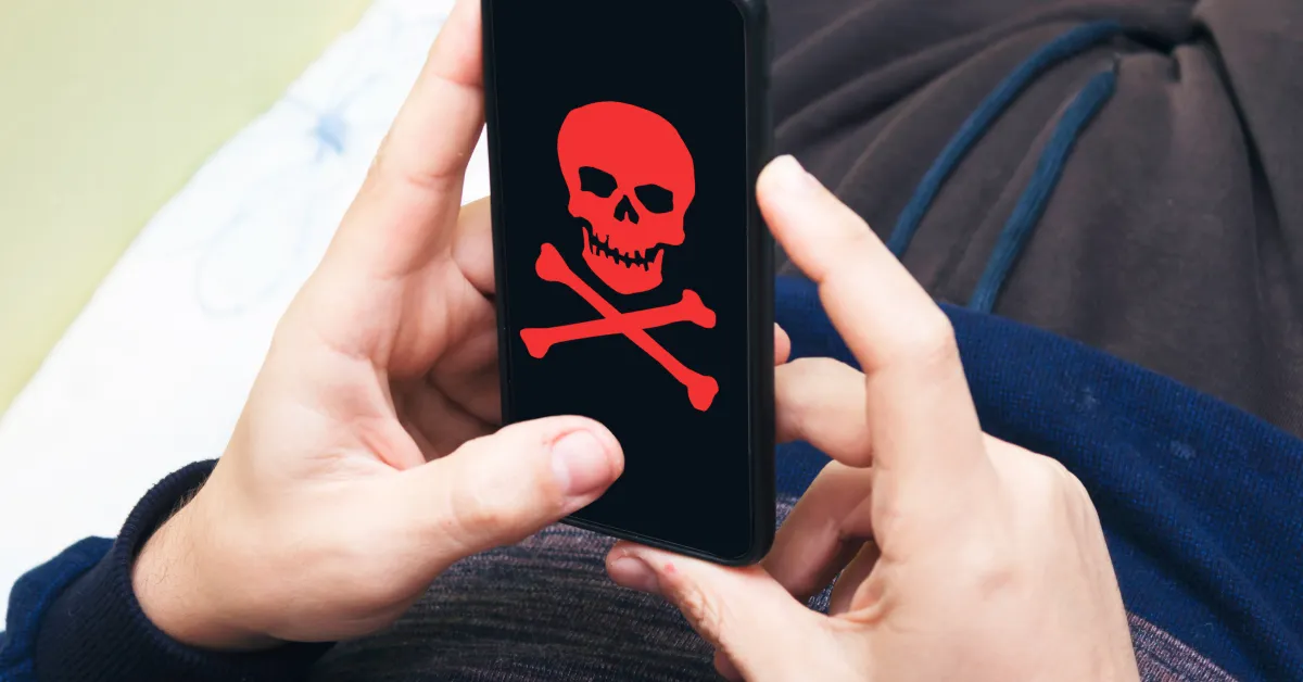 Person holding phone with skulls and cross-bone on display.