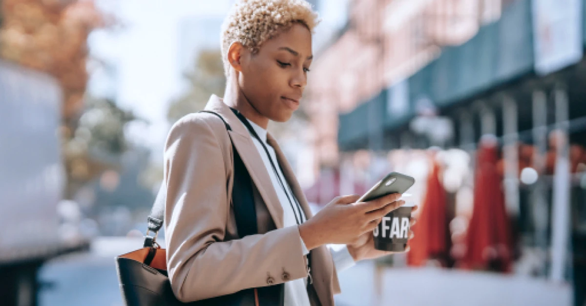 Focused woman messaging on smartphone on the sidewalk.