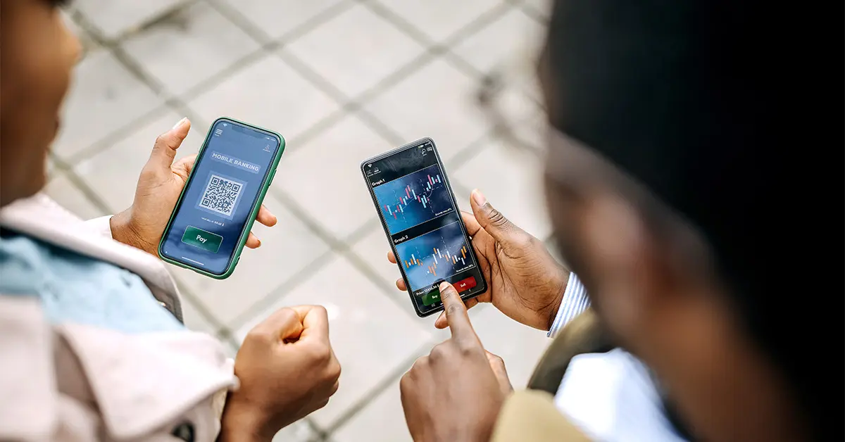 Two people talking and showing each other things on their phones.