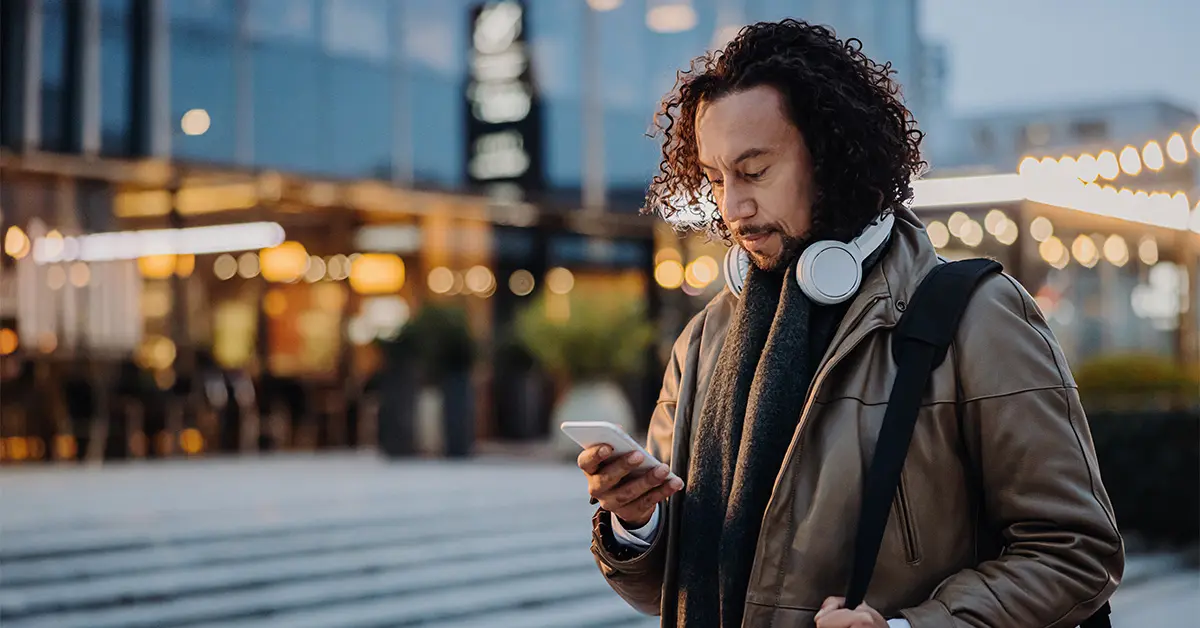 Business man walking while looking down at his phone.