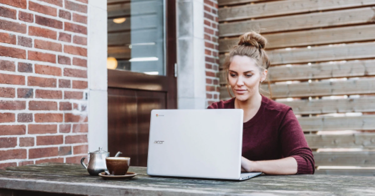 Woman working outside with a Chromebook.