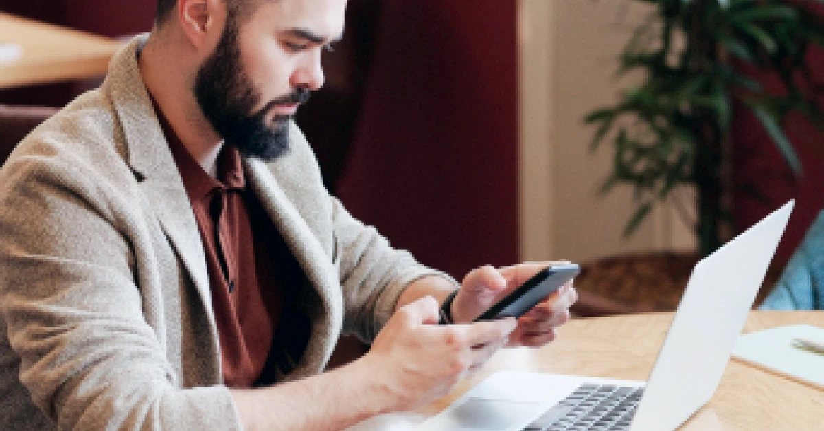Man working with smartphone and laptop in a cafe.